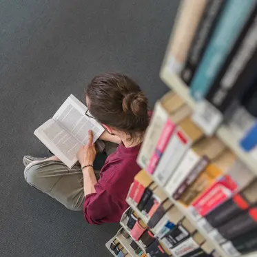 Student sitzt in der Bibliothek und liest ein Buch