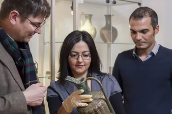 Der Inhaber der Professur fr Islamische Kunstgeschichte und Arch?ologie (li.) Lorenz Korn steht mit zwei Studierenden vor einer Vitrine mit Vasen im Bamberger Universit?tsmuseum fr Islamische Kunst. Alle drei schauen auf eine Vase, die die Studentin in den H?nden h?lt.  