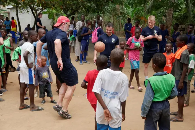 Otto J. Band und seine Auswahlmannschaft spielen mit Kindern an der Elfenbeinkste Fu?ball.