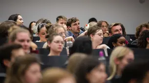 A frontal photo of the audience during the Q&A. The male student asking a question is at the center of the photo.